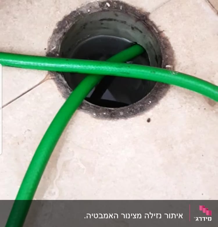 צינור ירוק נכנס לפתח ניקוז ברצפה